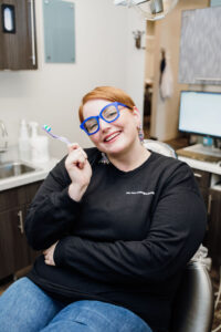 How to prevent cavities: brush your teeth twice a day like one of our patients pictured who is holding a toothbrush.